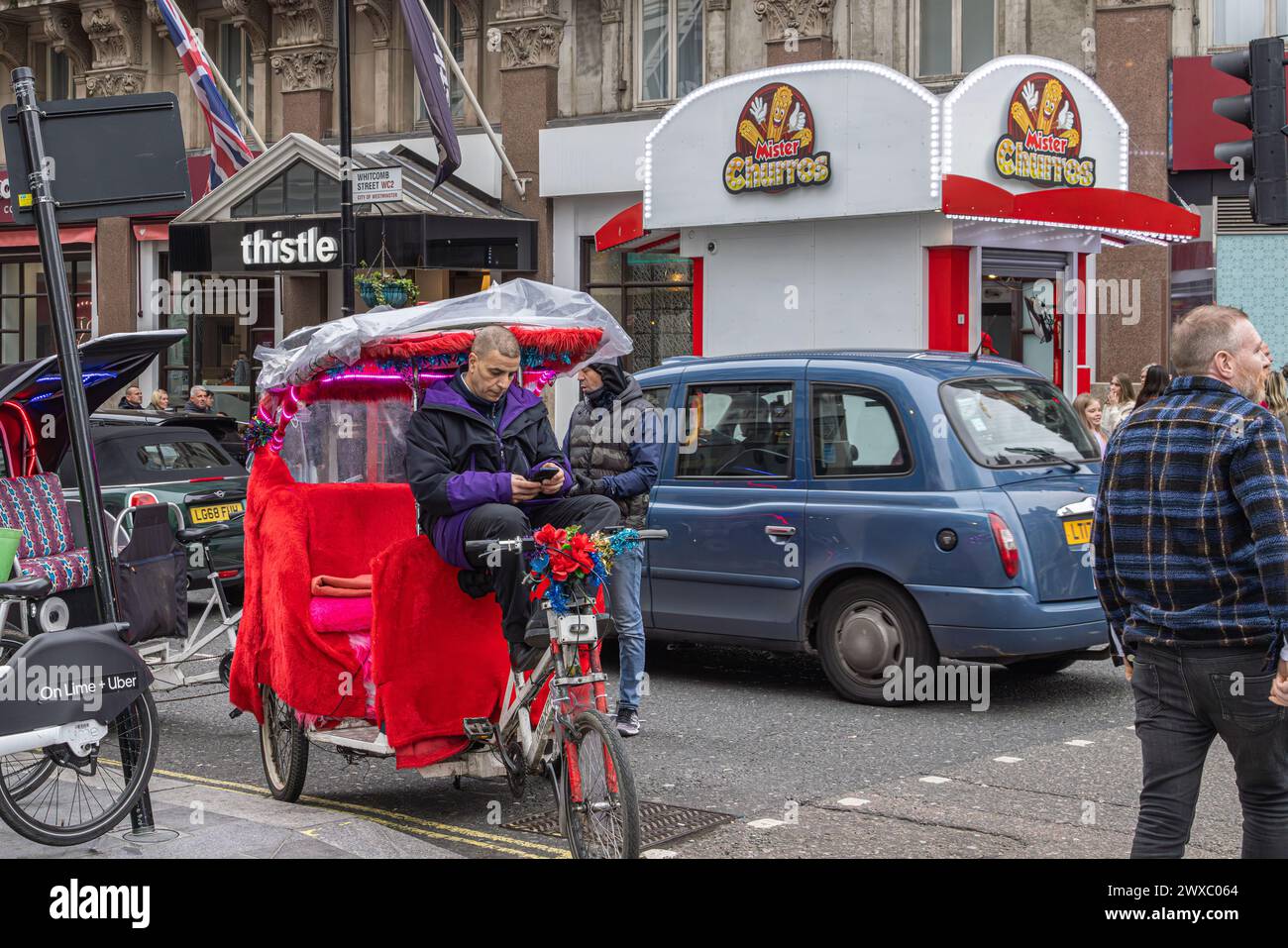 Un pédicab ou un pousse-pousse regarde son téléphone en attendant son prochain client. Le Pedicabs London Bill réglementera les tarifs et améliorera la sécurité. Banque D'Images
