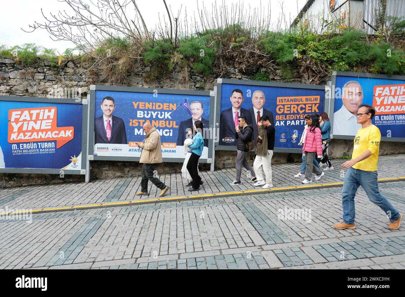 Istanbul Turquie - mars 2024 - Un guide guide guide un groupe de touristes devant les affiches de la campagne électorale locale pour les candidats du parti AK Banque D'Images