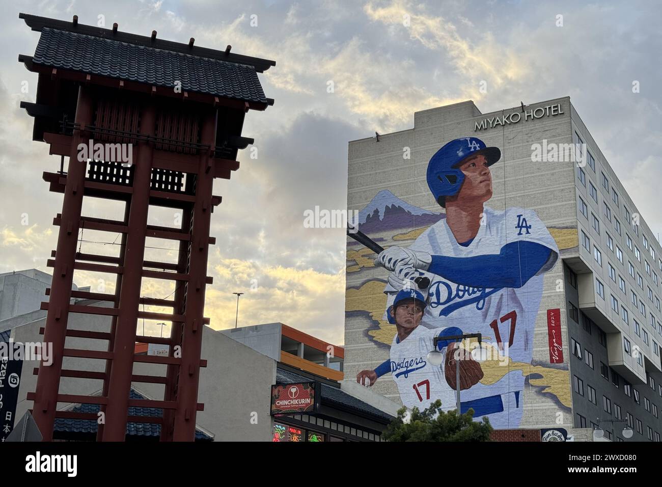 Une murale des Los Angeles Dodgers désigné frappeur Shohei Ohtani sur le côté de l'hôtel Miyako dans le quartier Little Tokyo de Los Angeles avec la ligne d'horizon du centre-ville comme toile de fond le vendredi 29 mars 2024. Banque D'Images