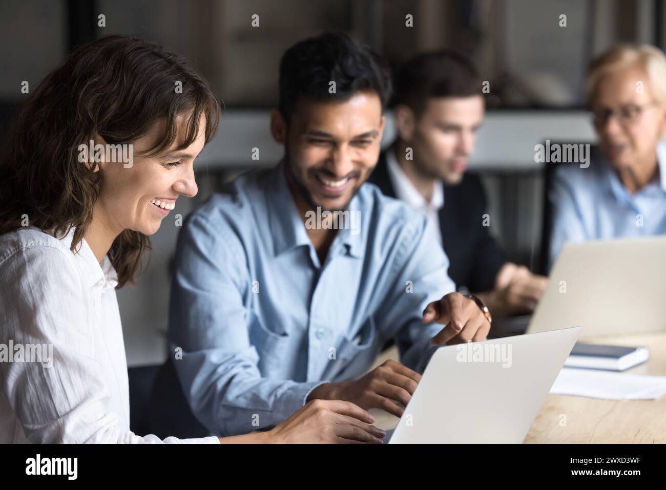 Collègues multiethniques joyeux parlant et riant de l'ordinateur portable Banque D'Images