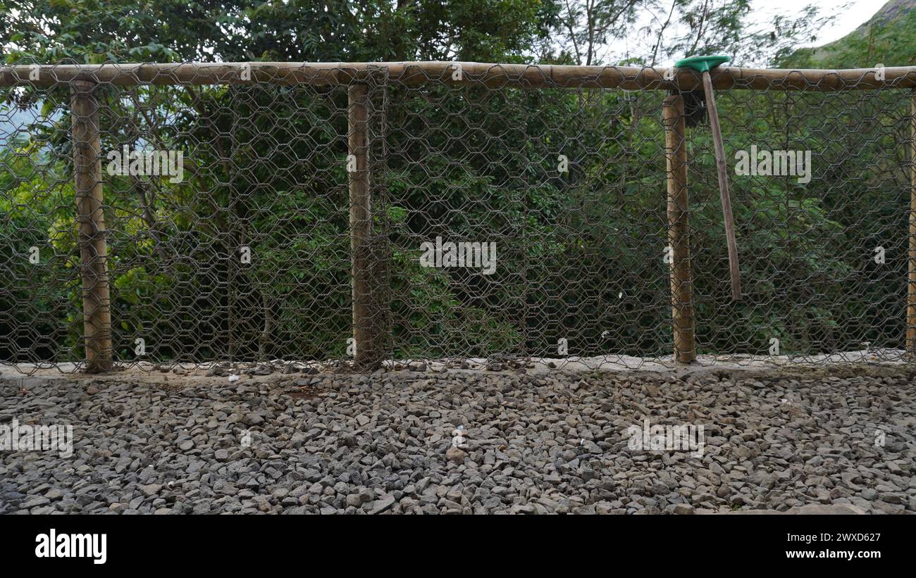 Une clôture métallique installée pour protéger les gens de tomber dans un ravin avec du gravier en dessous Banque D'Images