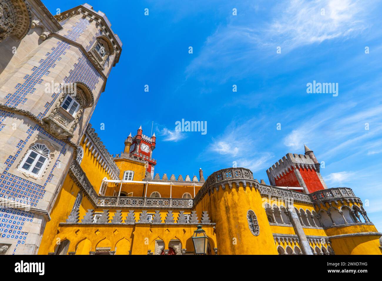 Vue extérieure grand angle du Palais de Pena avec des murs de couleur jaune et rouge et des mosaïques sur le mur et les murs fortifiés, sous un ciel bleu ensoleillé. Sintra Banque D'Images