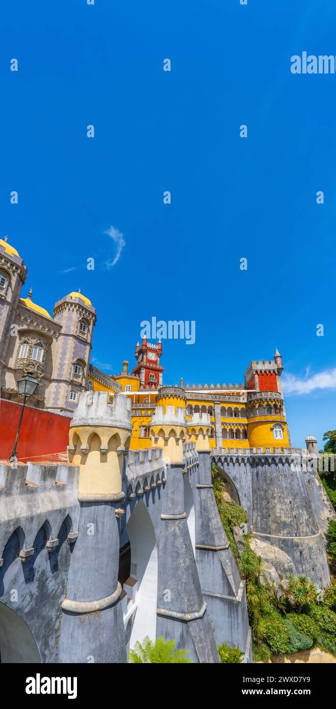 Vue extérieure du Palais de Pena avec des murs de couleur jaune et rouge et des mosaïques sur la colline avec le mur et les murs fortifiés, sous un ciel bleu ensoleillé. Péché Banque D'Images