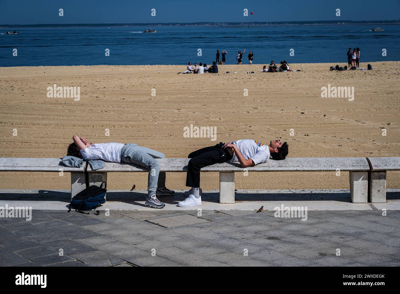 Arcachon, France — 22 mars 2024. Deux jeunes hommes se détendent au soleil sur la plage d'Arcachon, France. Banque D'Images
