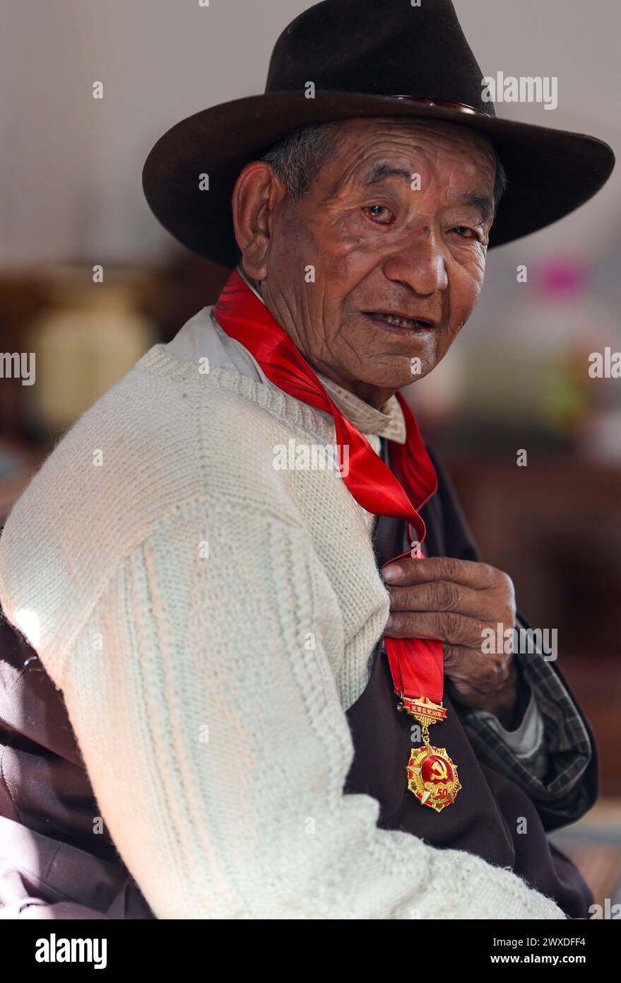 (240330) -- LHASSA, 30 mars 2024 (Xinhua) -- Drakpa Wangden, âgé de 80 ans, montre sa médaille commémorative décernée aux membres du Parti communiste chinois (PCC) après cinq décennies d'adhésion au Parti à Lhassa, dans la région autonome de Xizang, dans le sud-ouest de la Chine, le 11 mars 2024. Né en 1944, Drakpa Wangden vit maintenant dans le district de Doilungdeqen à Lhassa, dans la région autonome de Xizang, au sud-ouest de la Chine. Avant la réforme démocratique, Drakpa Wangden et sa famille étaient serfs, travaillant sur des manoirs affiliés à deux monastères de l'actuelle Lhassa. Pour sa famille, chaque printemps signifiait emprunter des graines de leur mât Banque D'Images