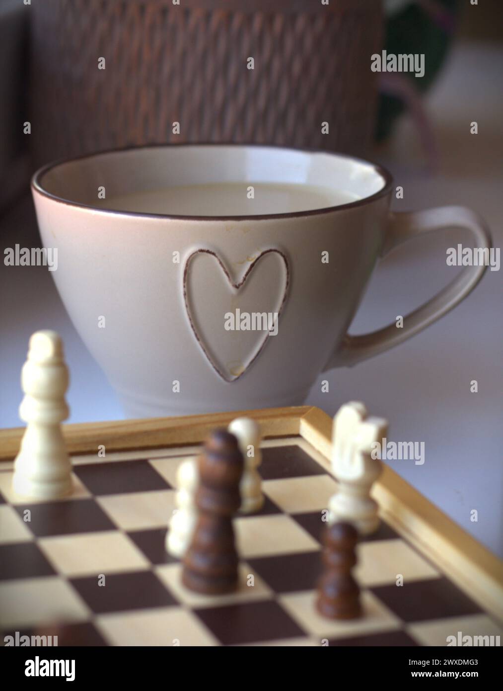 Jeu d'échecs - échiquier avec les pièces d'échecs et une tasse à café décorée avec un symbole de coeur Banque D'Images