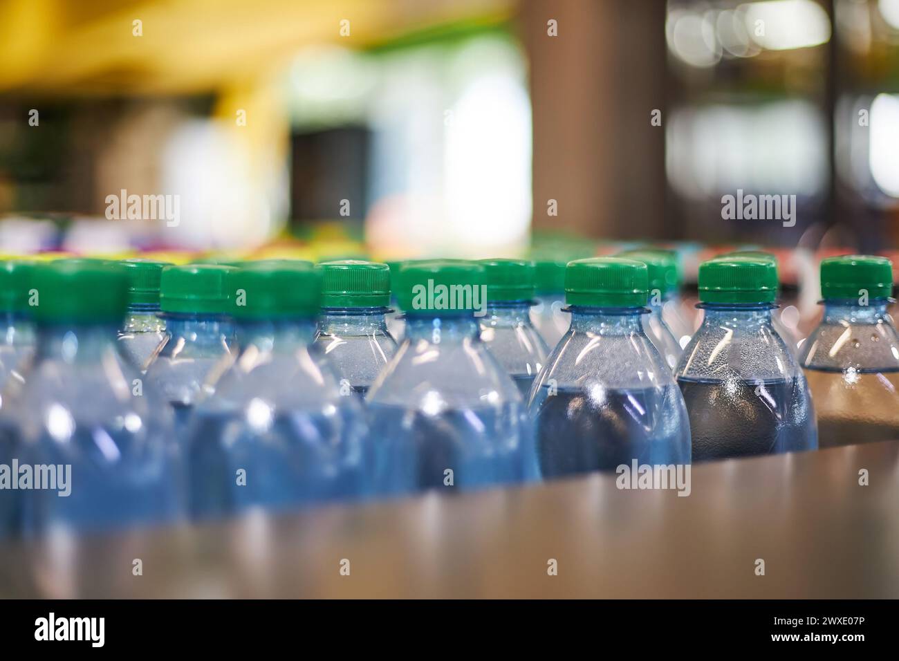 Bouteilles d'eau minérale de petit volume en plastique bleu d'un demi-litre avec bouchon vert en magasin, étagère de supermarché, gros plan. Forte consommation de plastique dans la vie quotidienne, ce qui pollue l'environnement Banque D'Images