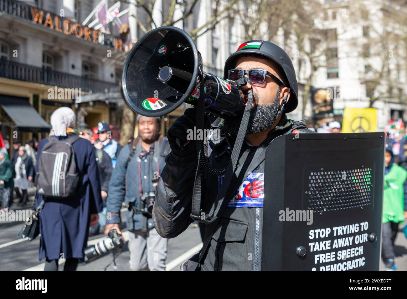 The Strand, Londres, Royaume-Uni. 30 mars 2024. Une manifestation est en cours contre l'escalade de l'action militaire à Gaza alors que le conflit entre Israël et le Hamas se poursuit. Organisés par des groupes tels que Palestine Solidarity Campaign et Stop the War Coalition, intitulés « manifestation nationale » et avec des appels à « Halte au génocide », « cessez-le-feu maintenant » et « Libérez la Palestine », les manifestants sont partis de Russell Square avant de se diriger vers Trafalgar Square. Mâle en uniforme de style paramilitaire utilisant le mégaphone. FOA Banque D'Images