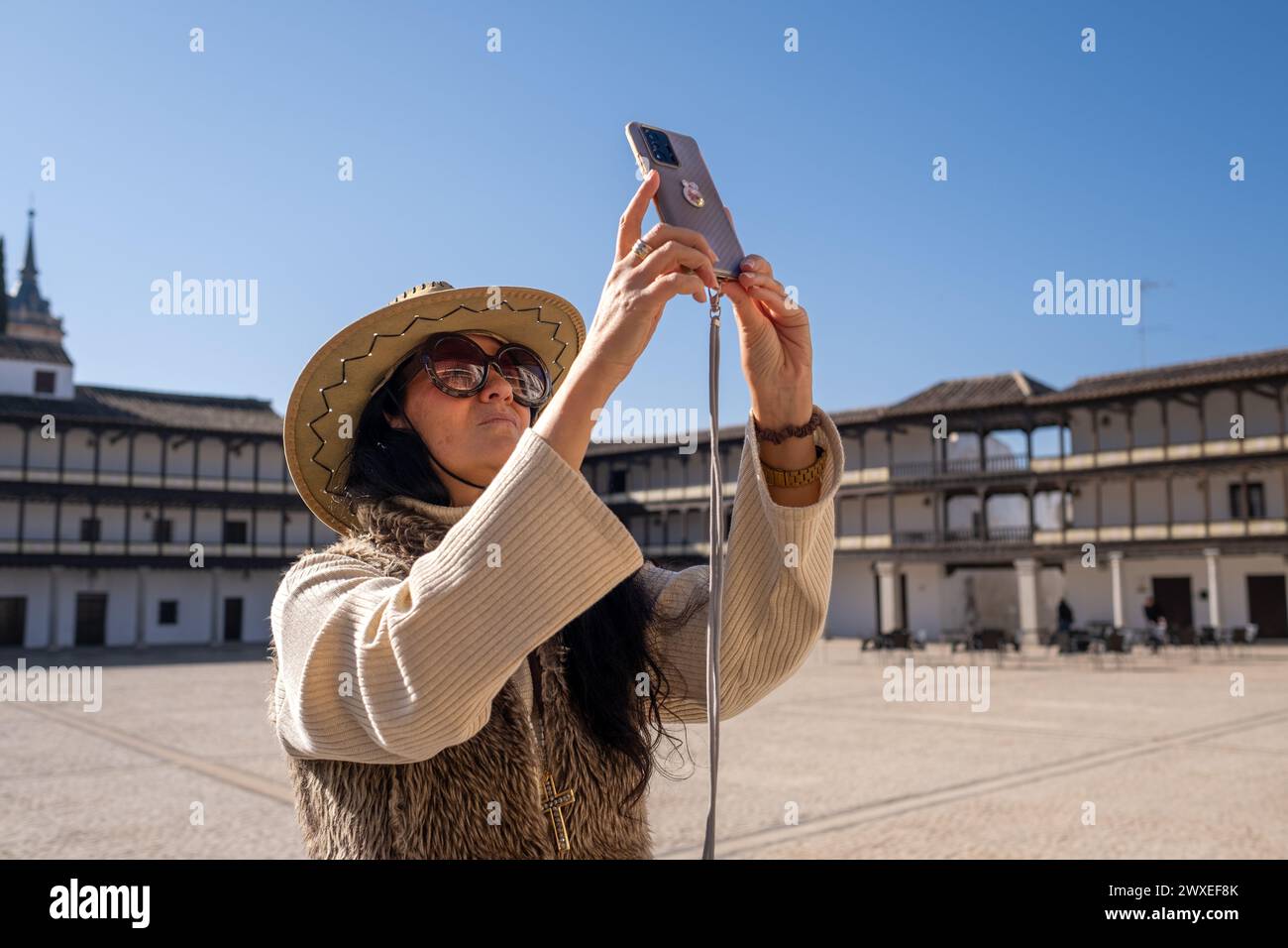 voyageuse d'âge moyen en gilet prenant une photo de la place historique. Sur la Plaza Mayor de Tembleque, à Tolède, dans la déroute Don Quichotte à Castilla L. Banque D'Images