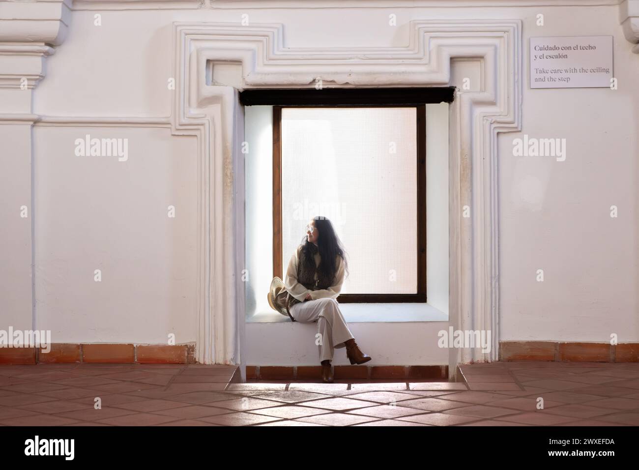 Une femme d'âge moyen portant un chapeau se repose de sa journée de visites dans l'une des salles de l'église de San Agustin à Almagro, Ciudad Real, Espagne. T Banque D'Images