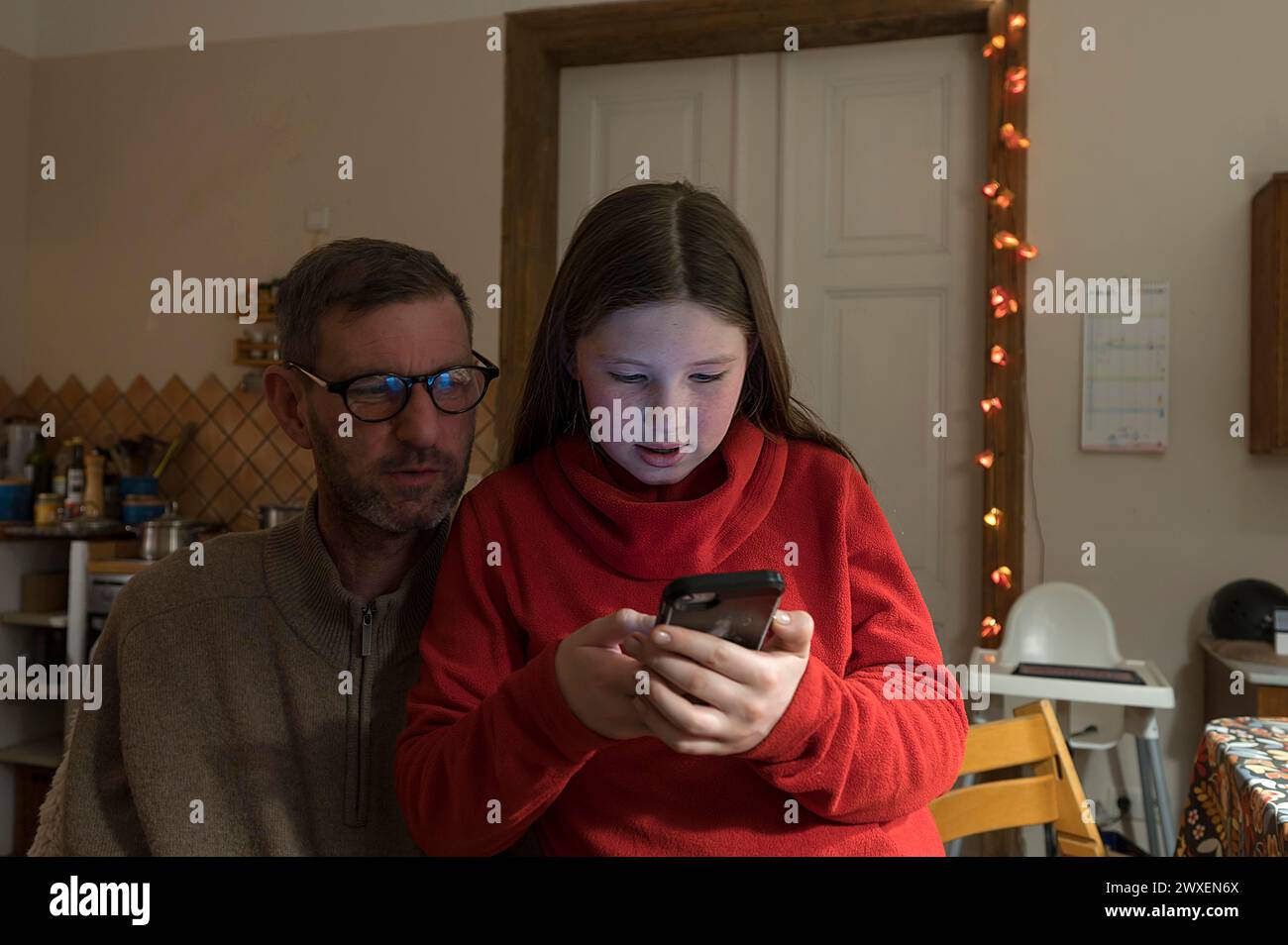 Fille, 10 ans, sur le téléphone portable, père regardant, Mecklenurg-Vorpommern, Allemagne Banque D'Images