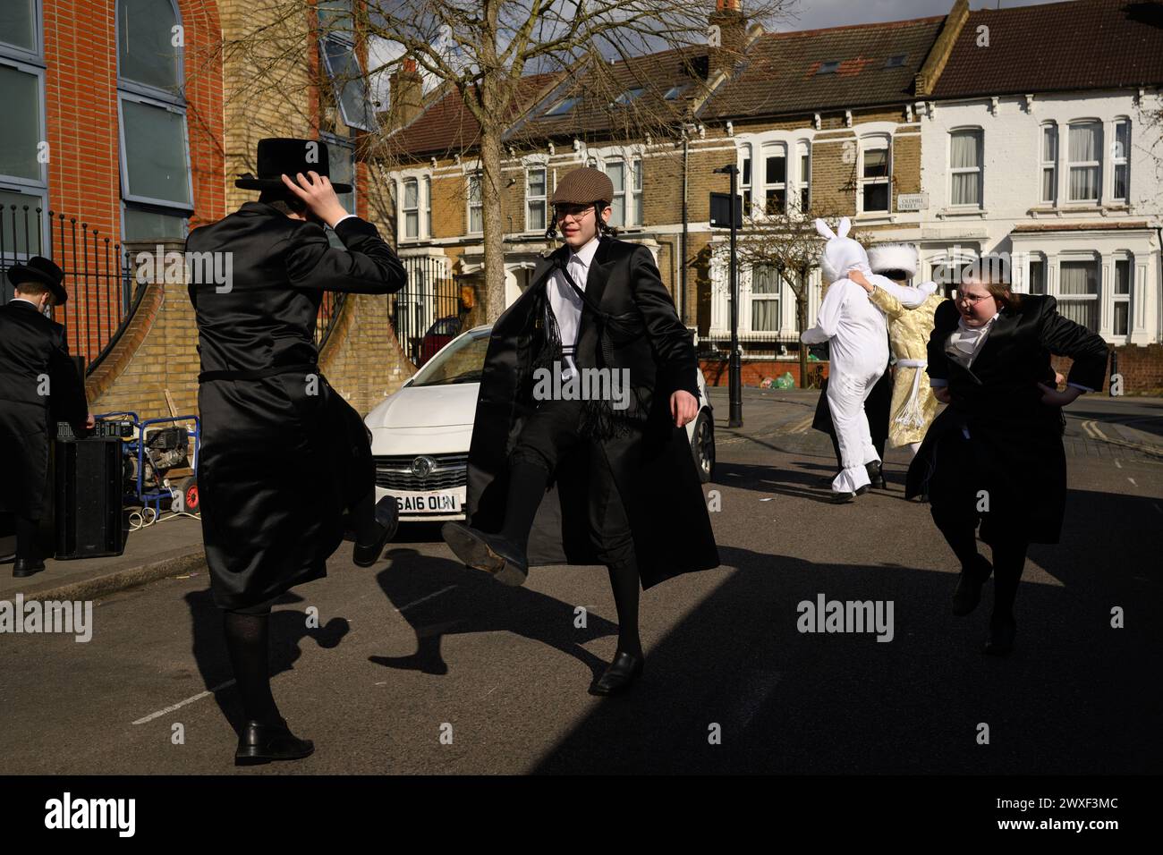 LONDRES, Royaume-Uni, 24 mars. La communauté juive de Stamford Hill, Londres célèbre la fête religieuse de Pourim. Les jeunes hommes dansent dans les rues et les enfants s'habillent de masques et de costumes. Banque D'Images