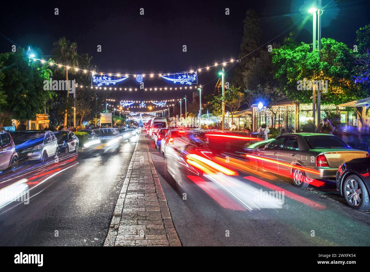 Rue principale Sderot ben Gourion à Haïfa la nuit brouillait les touristes de mouvement et la circulation automobile et la publicité au néon là-bas et les voitures dans les parkings Banque D'Images