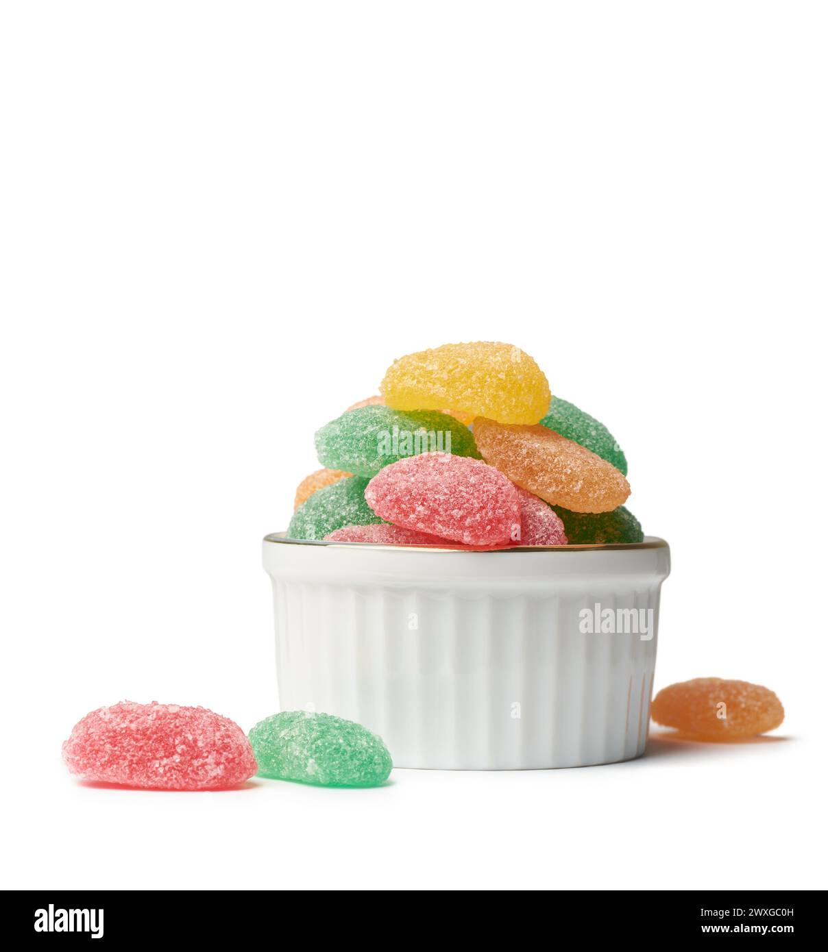 jujubes, confiserie de bonbons à mâcher gommeux colorée aromatisée aux fruits avec forme allongée sur une tasse blanche dispersée sur fond blanc isolé Banque D'Images