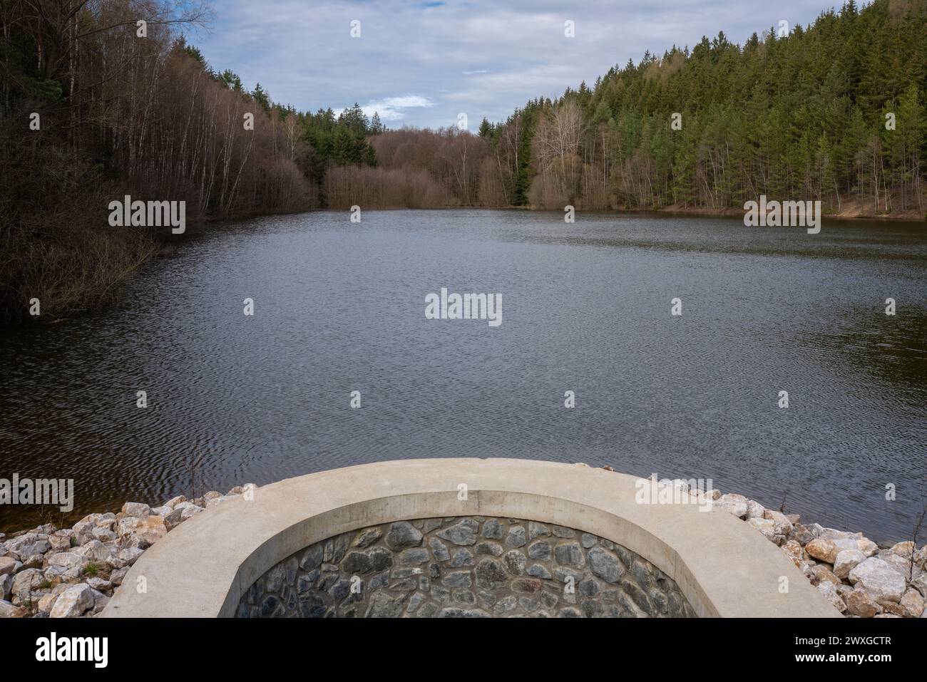 Étang de Wolmannův rybník dans la zone paysagère protégée de Křivoklátsko vu de son barrage. Un petit lac artificiel dans une forêt. Banque D'Images
