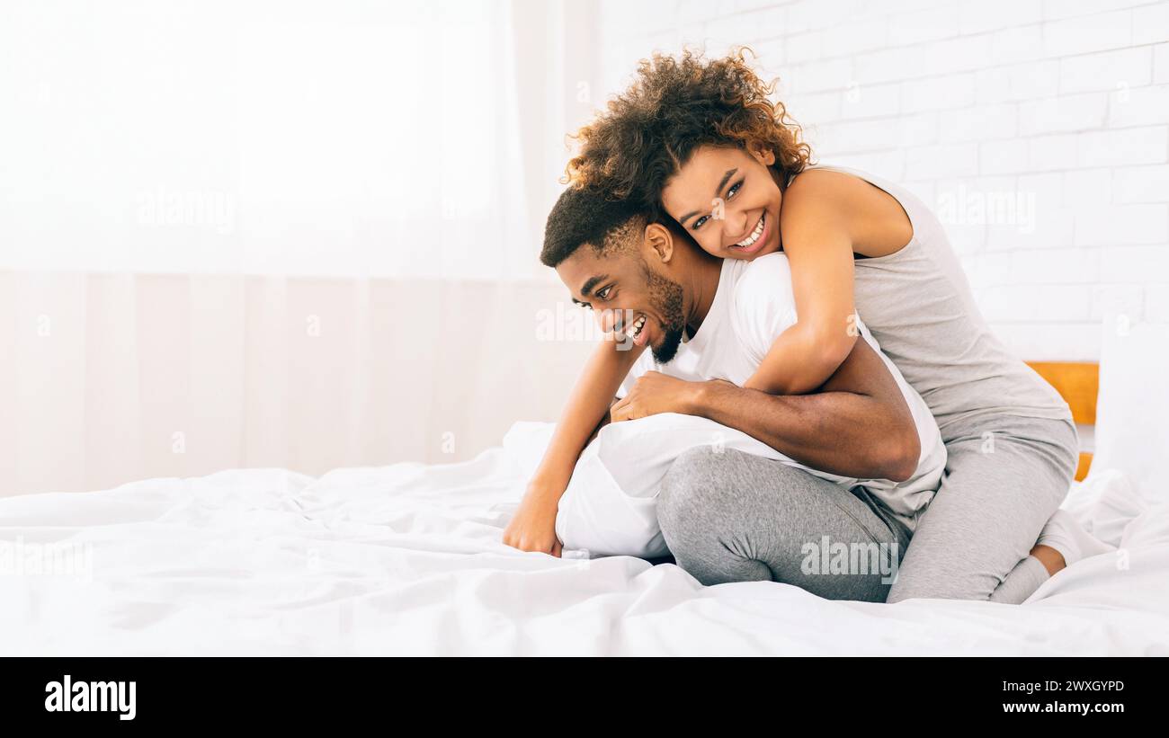 Heureux couple afro-américain aimant se liant dans le lit Banque D'Images