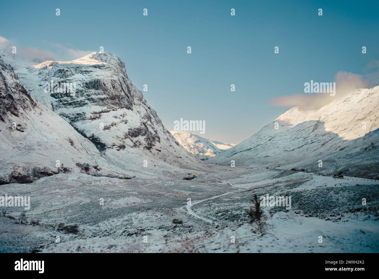 Un chemin serpente à travers un paysage enneigé avec les montagnes des trois Sœurs qui s’élèvent sur la gauche. Glencoe, Highlands écossais Banque D'Images