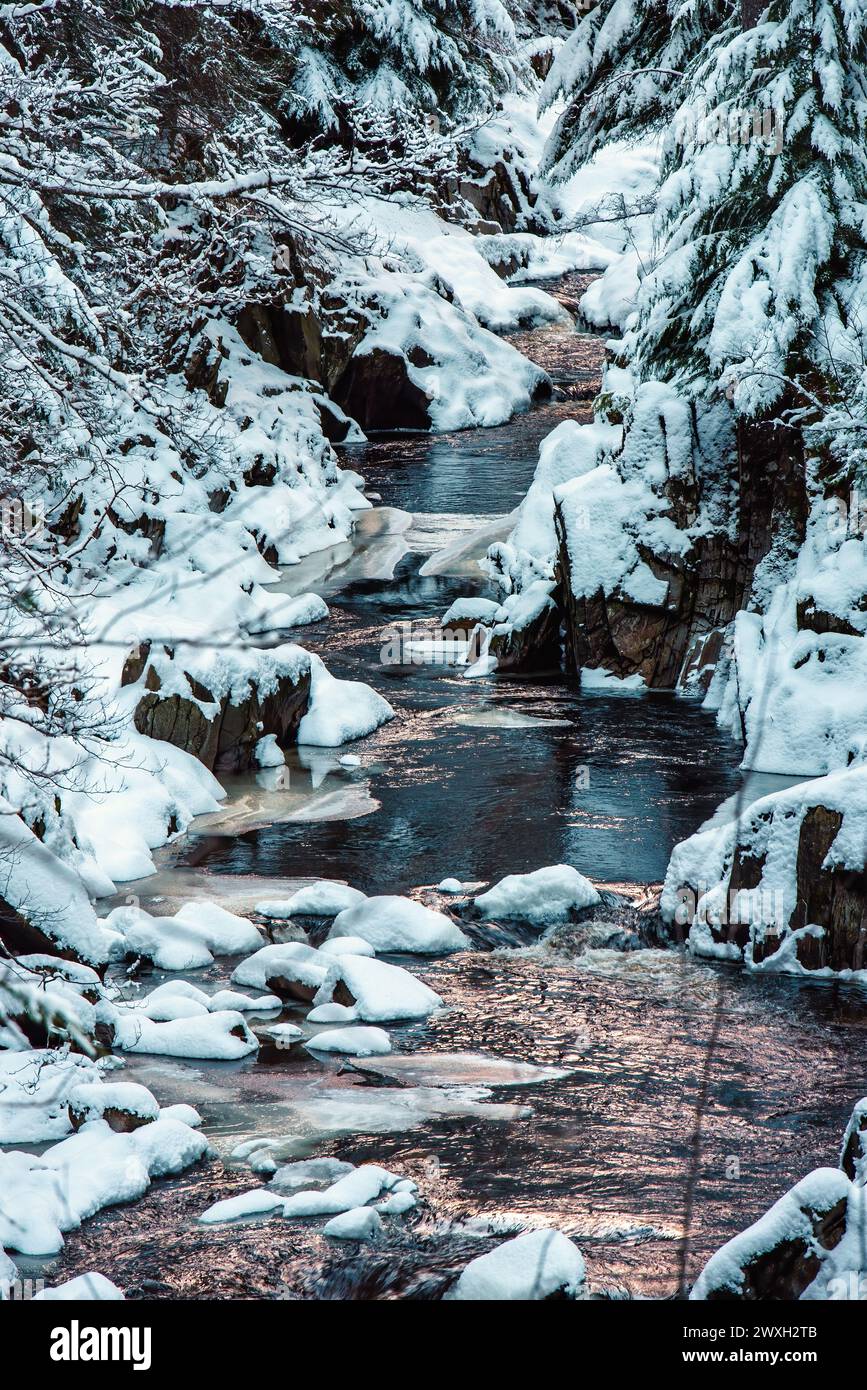River Pattack dans les Highlands écossais, avec des rochers enneigés et des arbres de chaque côté Banque D'Images