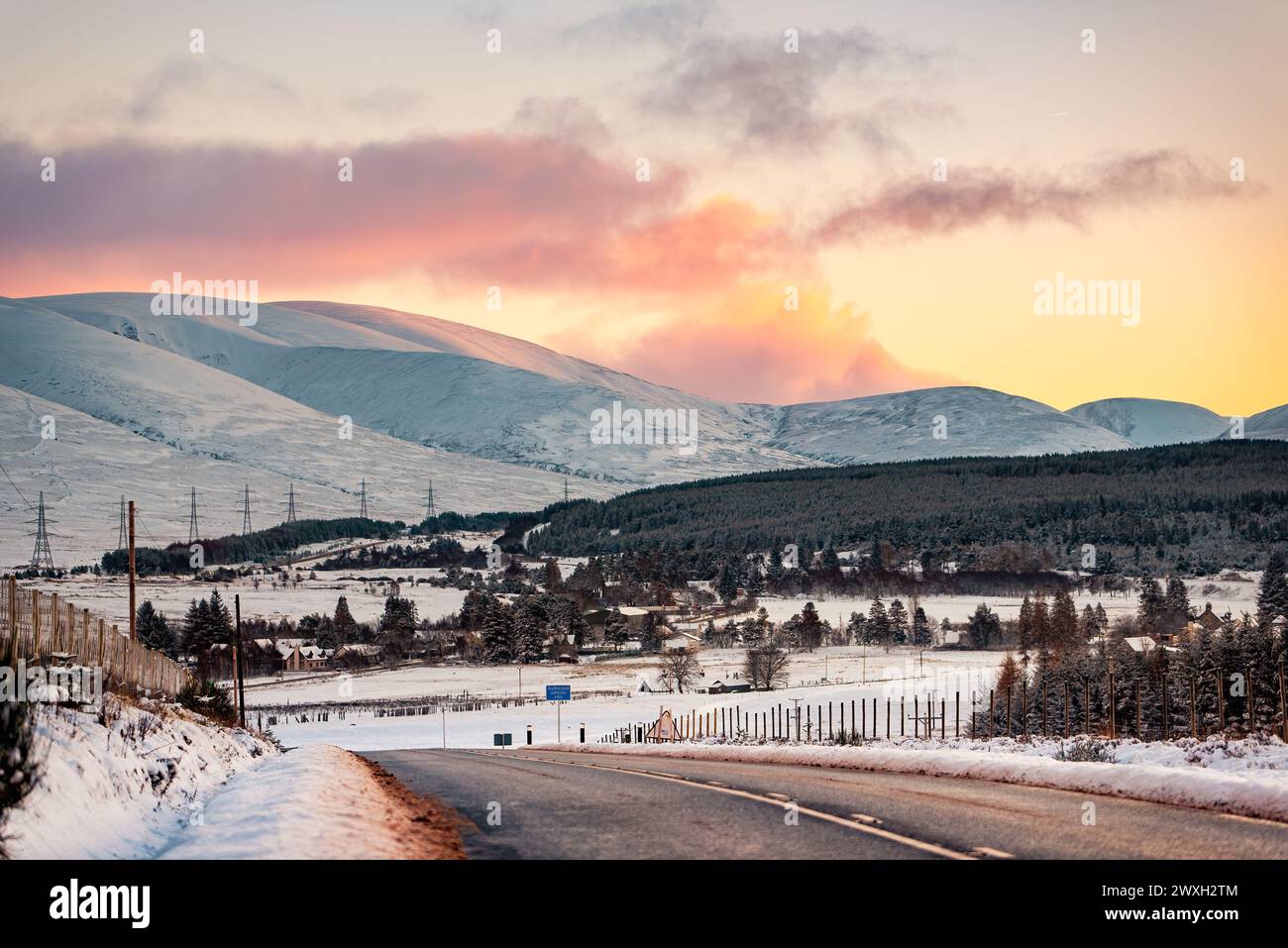 Le village de Dalwhinnie en Écosse, sur fond de montagnes enneigées sous un coucher de soleil rose Banque D'Images