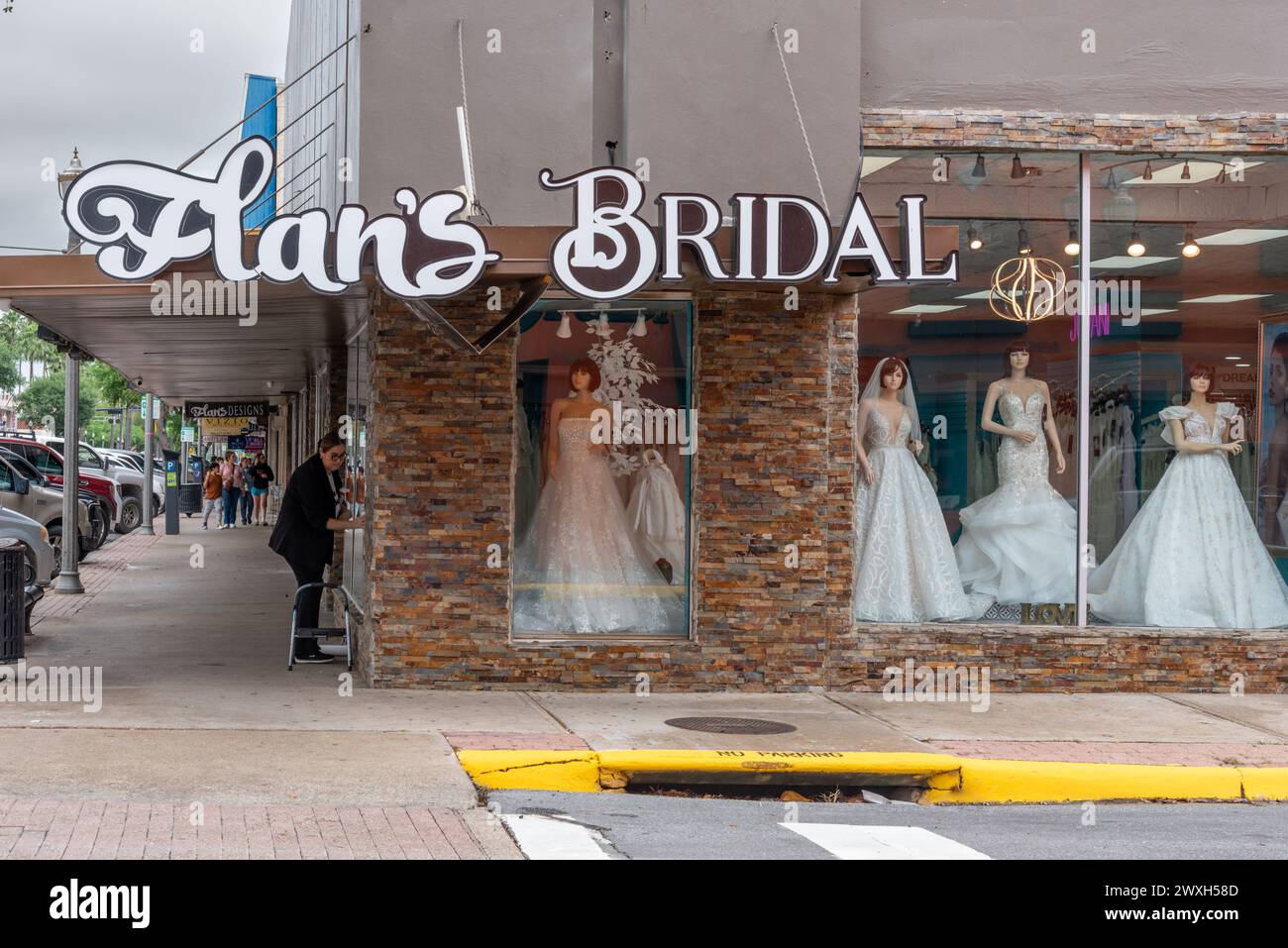 Extérieur de Flan's Bridal shop avec mannequins portant des robes de mariée blanches dans le centre-ville de McAllen, comté de Hidalgo, Texas, États-Unis. Une femme lave les fenêtres. Banque D'Images