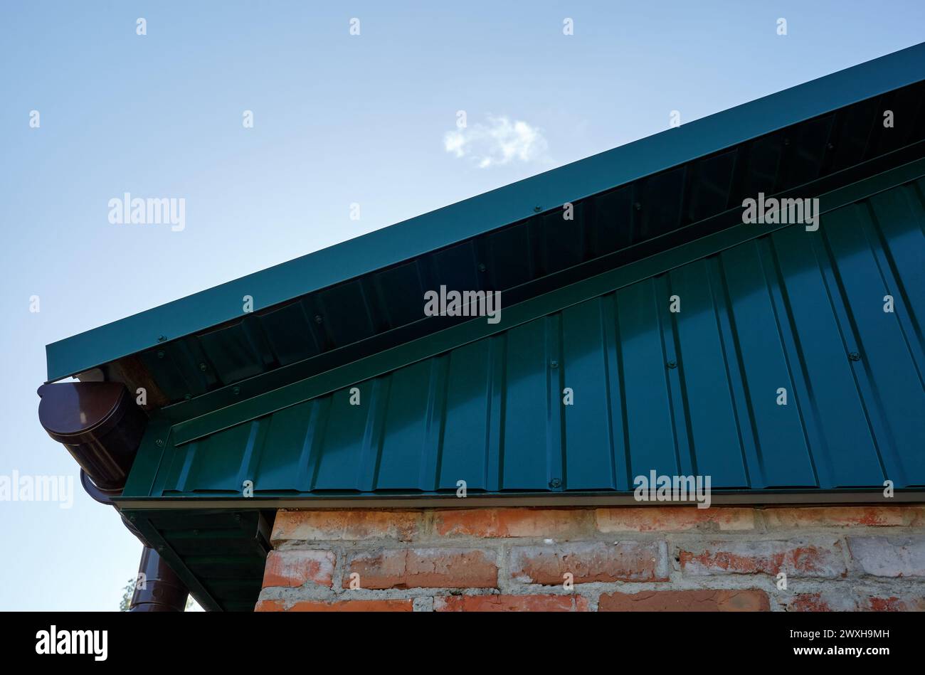 Fragment de toiture métallique de bâtiment rural. Système de drainage de gouttière de support sur le toit Banque D'Images