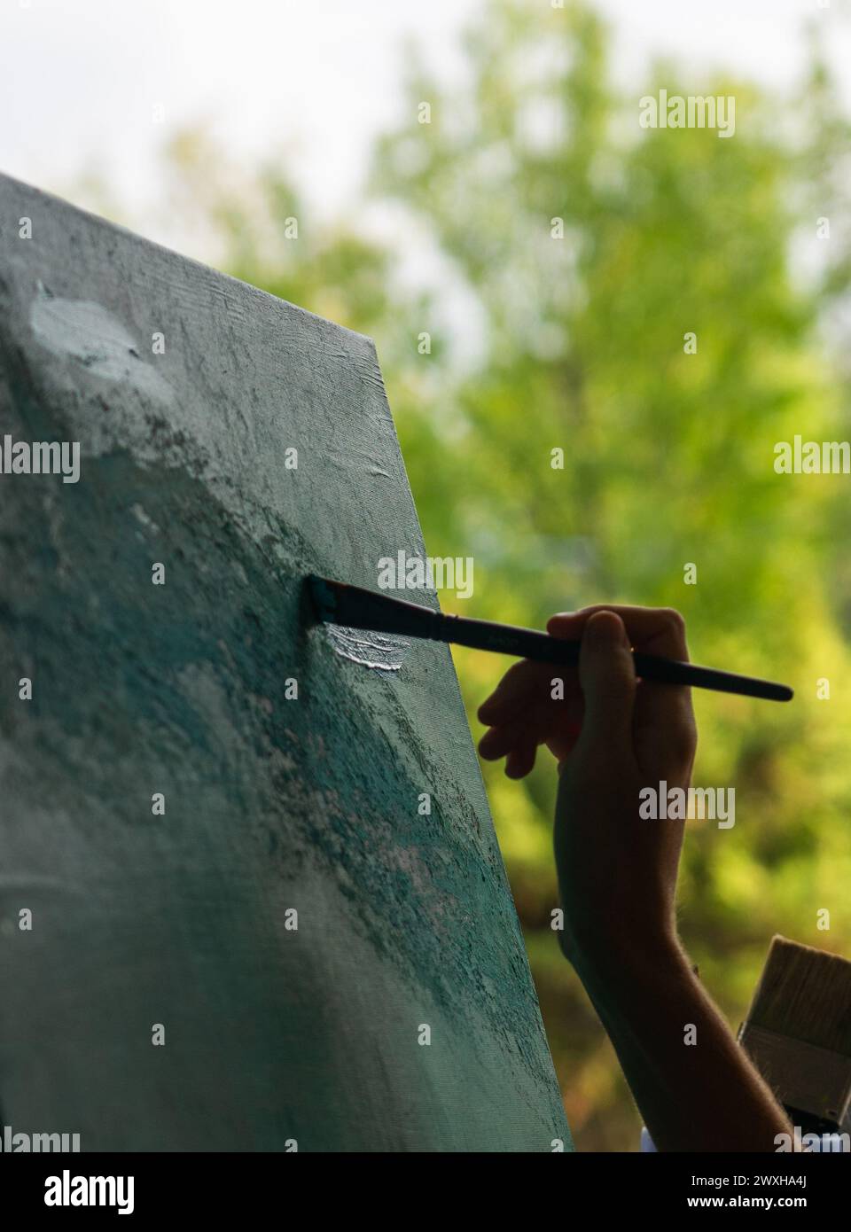 Main de femme peignant une toile avec un pinceau Banque D'Images