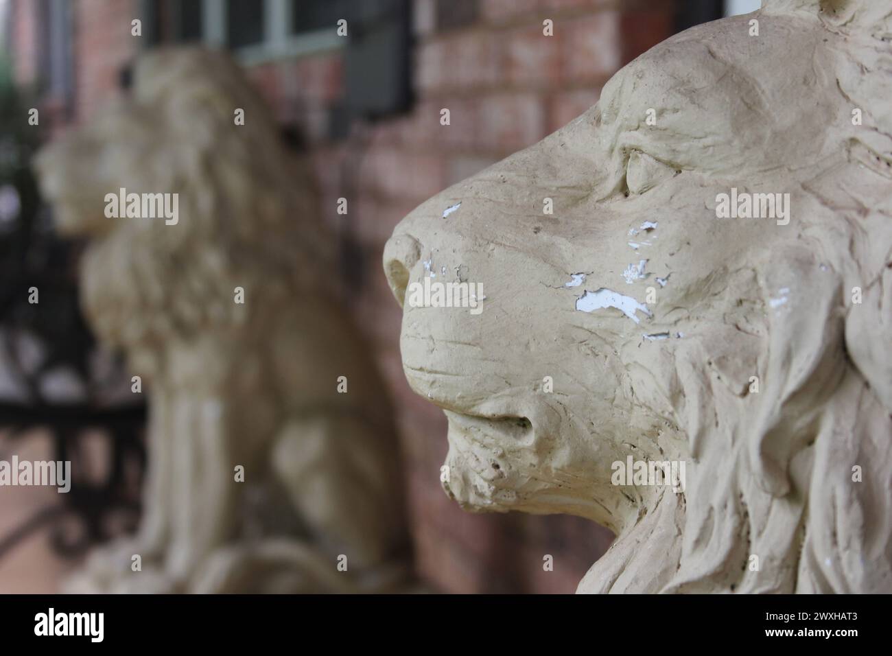 Deux statues de lion montent la garde à l'extérieur d'un ancien bâtiment en briques avec des fenêtres Banque D'Images