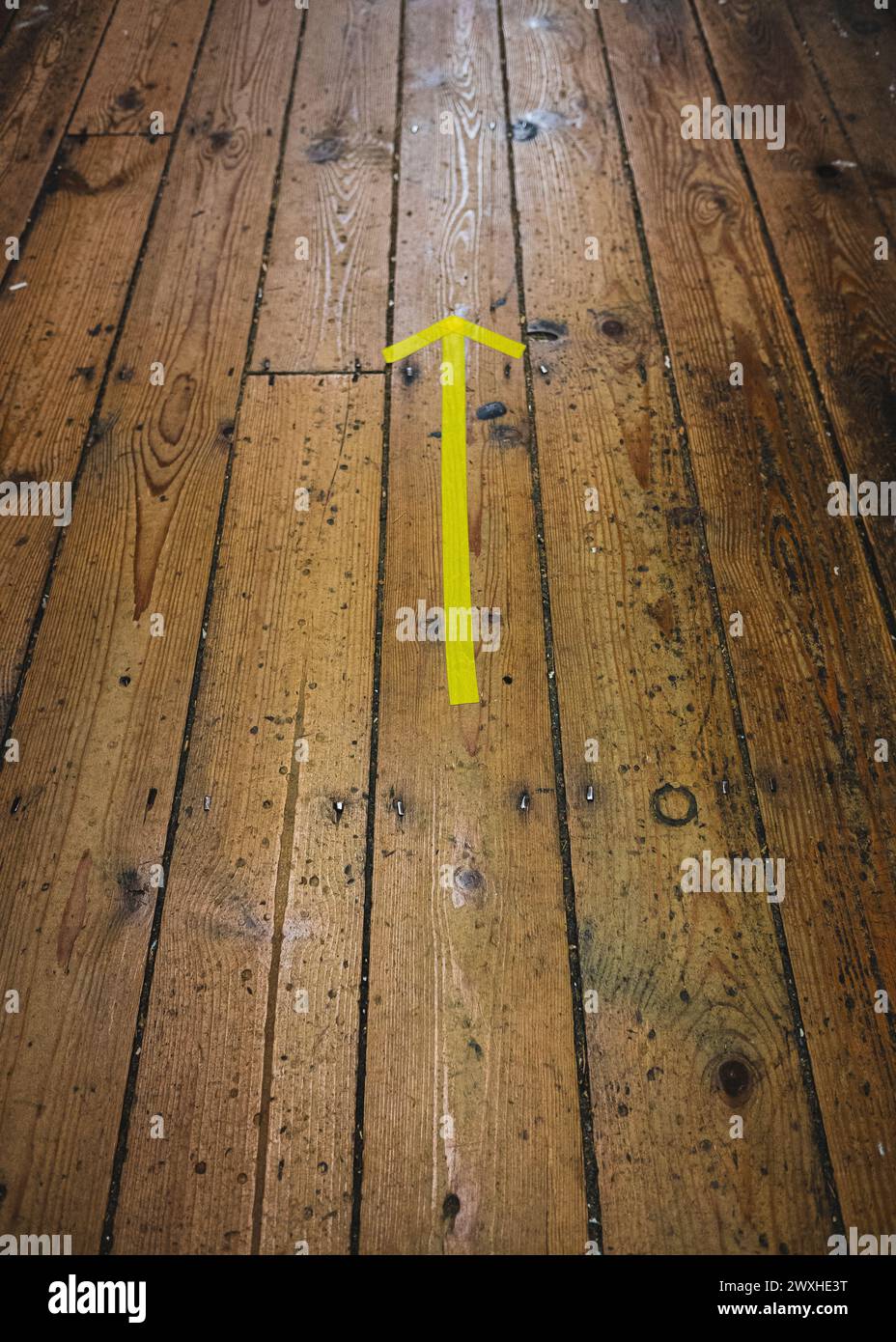 Flèche jaune sur le plancher en bois pointant vers l'avant Banque D'Images
