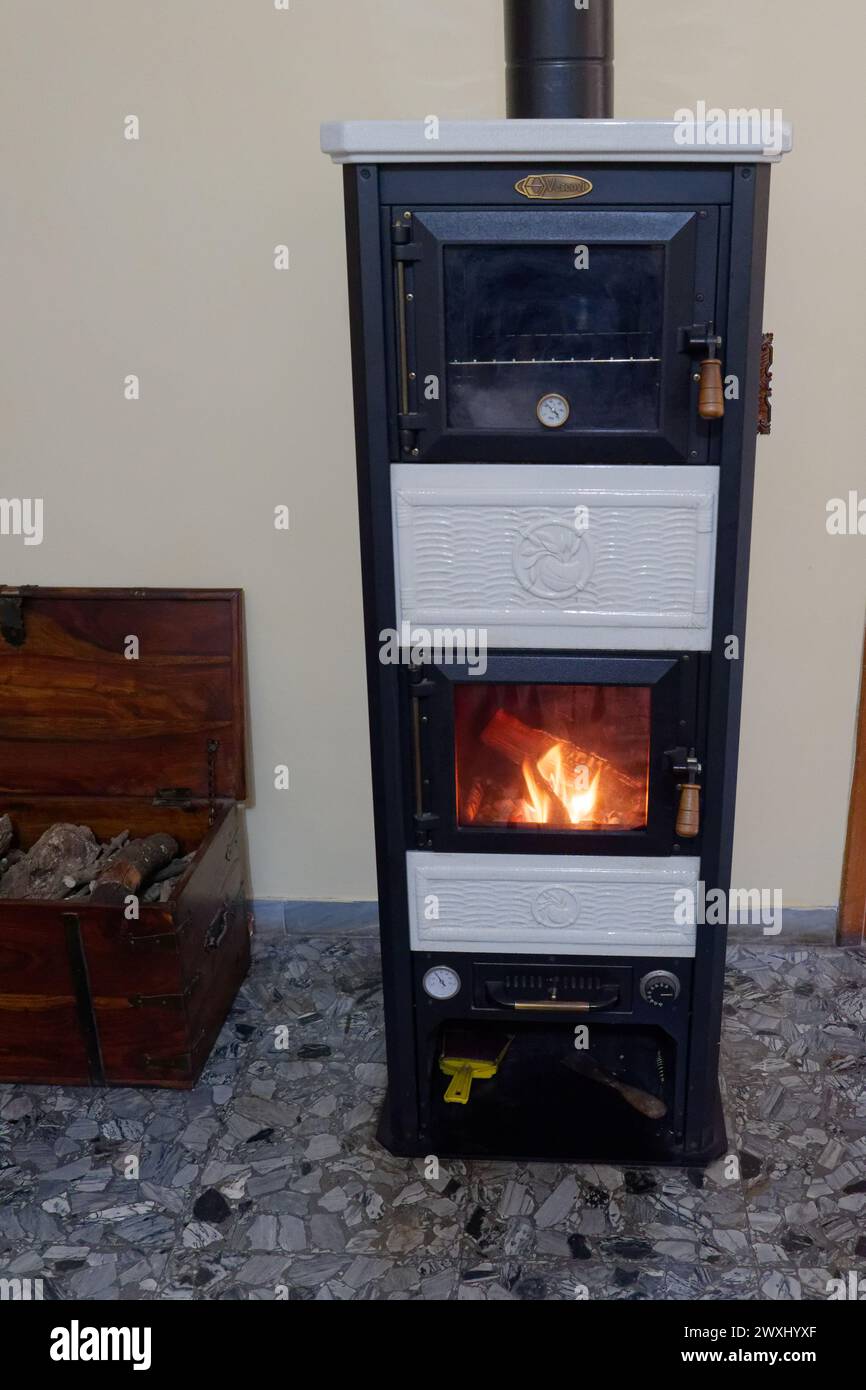 Vrai feu dans un poêle à bois et pile de bois dans une boîte dans un appartement à Montefiascone, région du Latium, Italie. 31 mars 2024 Banque D'Images