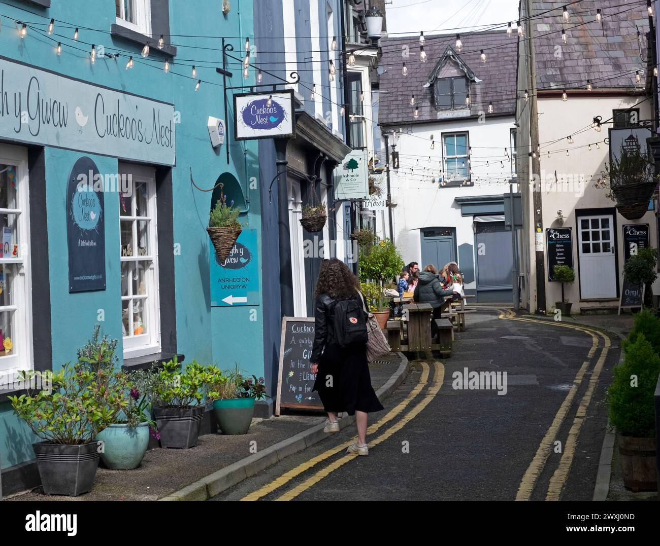 Femme sur Market Street vue arrière entrant dans Nyth y Gwcw Cuckoo's Nest boutique de cadeaux et les gens assis à des tables à l'extérieur Flow Llandeilo Wales UK Banque D'Images