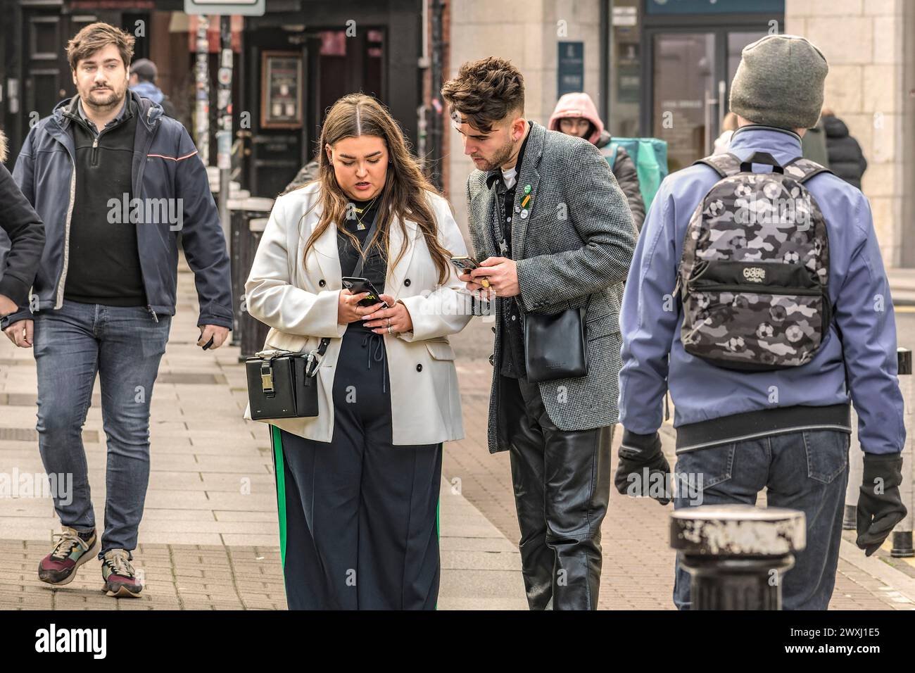 Conversation dans la rue. Une jeune femme montre quelque chose sur son téléphone à l'homme. Dublin. Irlande. Banque D'Images