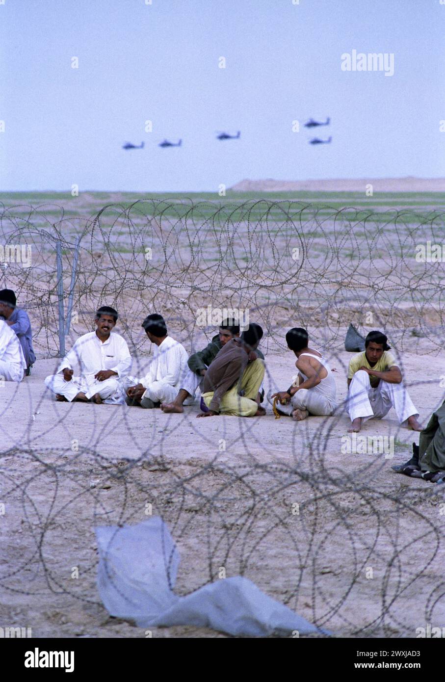 26 mars 1991 Un essaim d'hélicoptères Apache de l'armée américaine survolent des prisonniers de guerre irakiens dans un complexe temporaire de l'armée américaine dans le sud de l'Irak. Banque D'Images