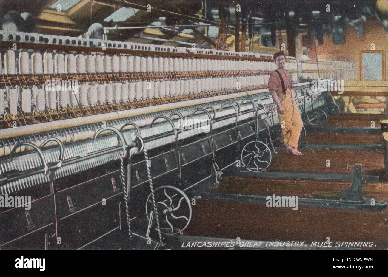 'Lancashire's Great Industry : mule Spinning' : photographie teintée en couleur publiée sous forme de carte postale par L. Pickles & Co, Bradford, au début du XXe siècle. Il montre un garçon appuyé contre une machine à filer à mule dans une usine de coton du Lancashire Banque D'Images