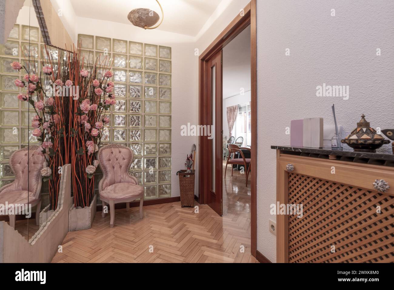 Hall d'entrée à la maison avec buffet en bois avec grand miroir intégré dans un panneau de marbre, mur de puits de lumière en briques de verre et planchers en chêne brillant Banque D'Images