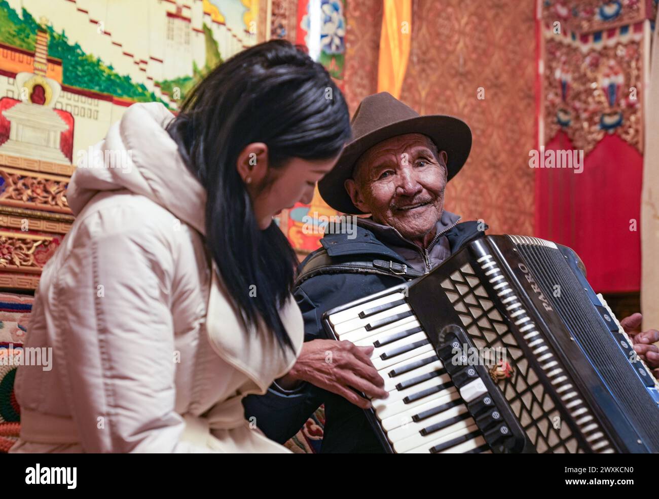 (240401) -- PÉKIN, 1er avril 2024 (Xinhua) -- Namgyal joue de l'accordéon avec sa petite-fille à côté chez lui dans le district de Doilungdeqen de Lhassa, dans la région autonome de Xizang, au sud-ouest de la Chine, 13 mars 2024. Né en 1945, Namgyal a grandi dans ce qui est maintenant le district de Doilungdeqen à Lhassa. Namgyal a rappelé que son pire souvenir était la pluie, qui s’infiltrait à travers le toit qui fuyait et mouillait son seul costume de vêtements, le laissant continuer à travailler pour le propriétaire du serf le lendemain dans des vêtements trempés. Après la réforme démocratique de 1959, la vie de Namgyal et de sa famille a totalement changé. Le fami Banque D'Images