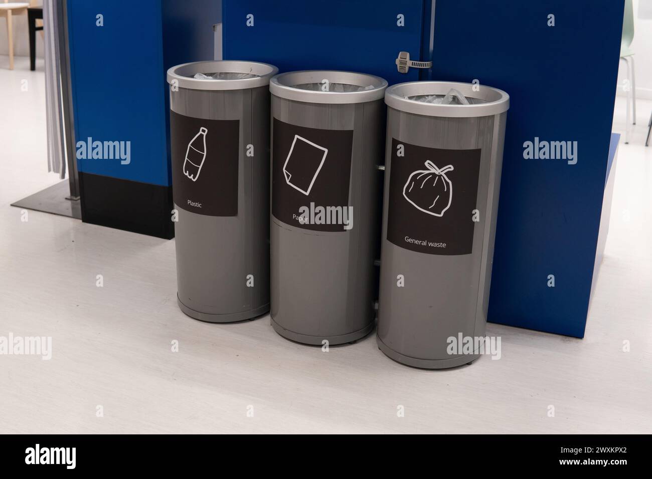 Une rangée de trois bacs de recyclage alignés les uns à côté des autres à l'intérieur. Les bacs sont étiquetés pour le plastique, le papier et les déchets généraux. Banque D'Images