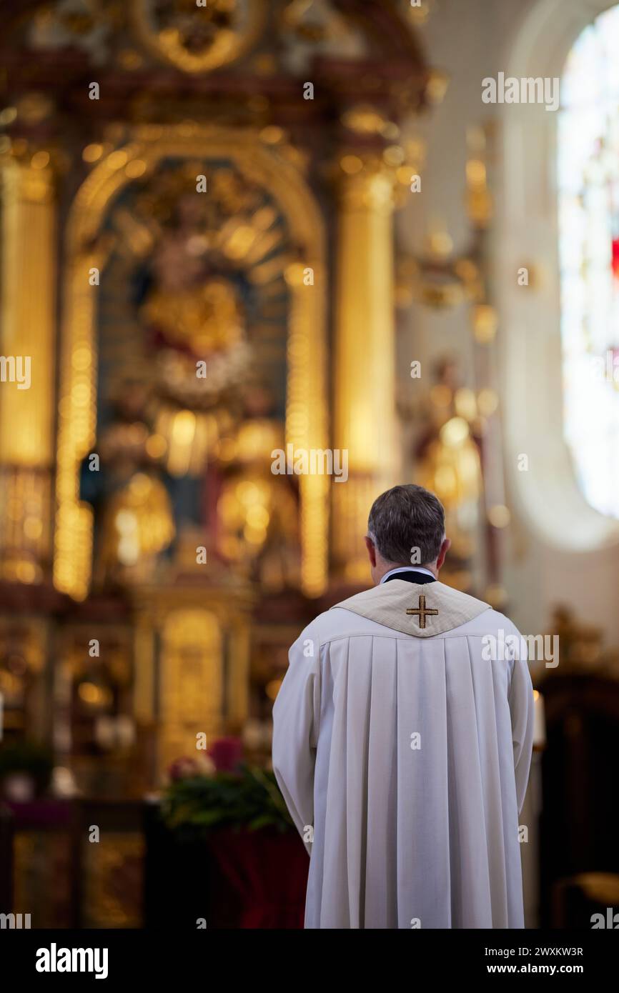 Un prêtre debout à l'autel dans une cathédrale, regardant vers le bas Banque D'Images
