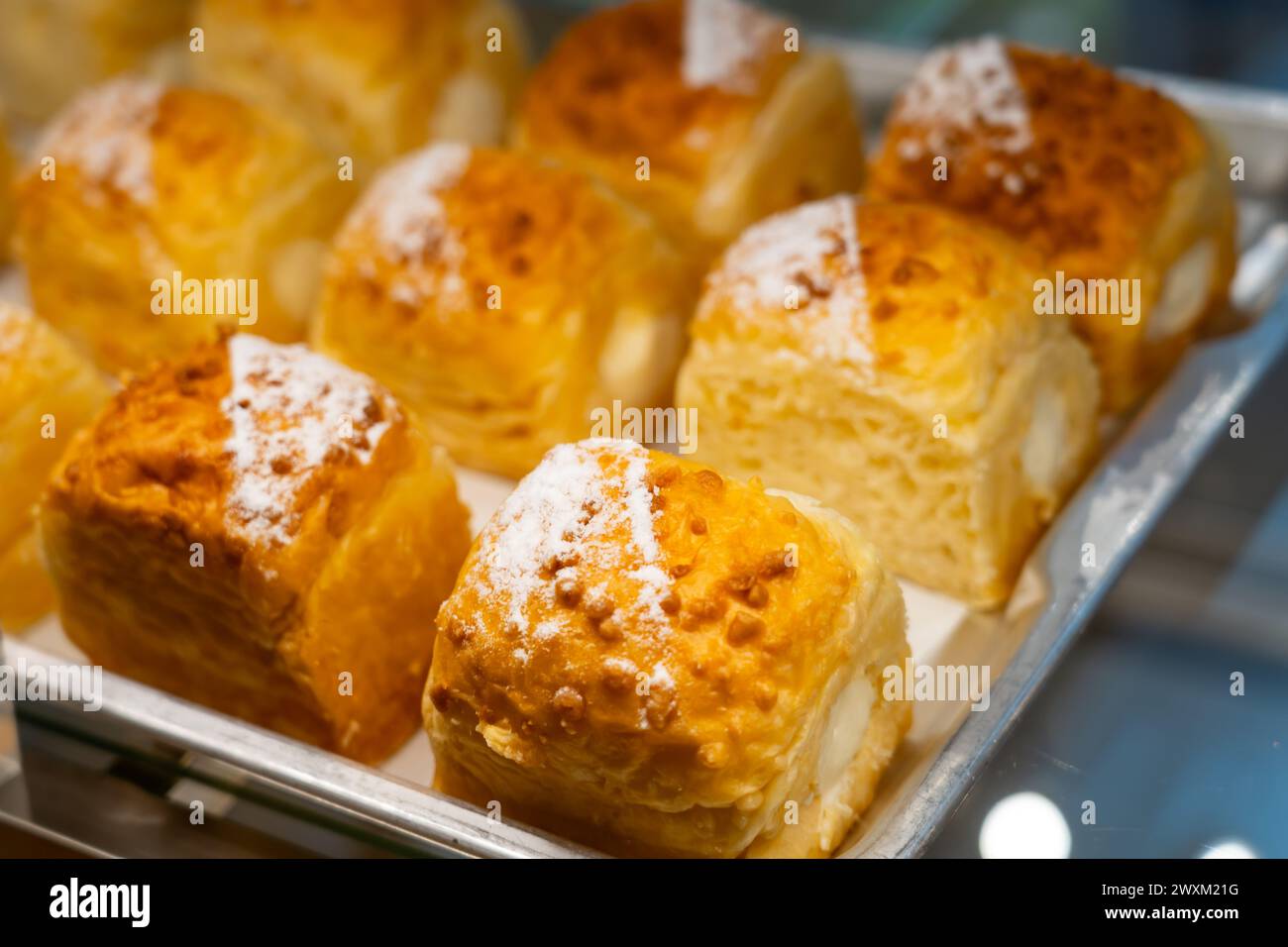 Petits pains luxuriants saupoudrés de sucre en poudre dans une belle vitrine de boulangerie. Banque D'Images