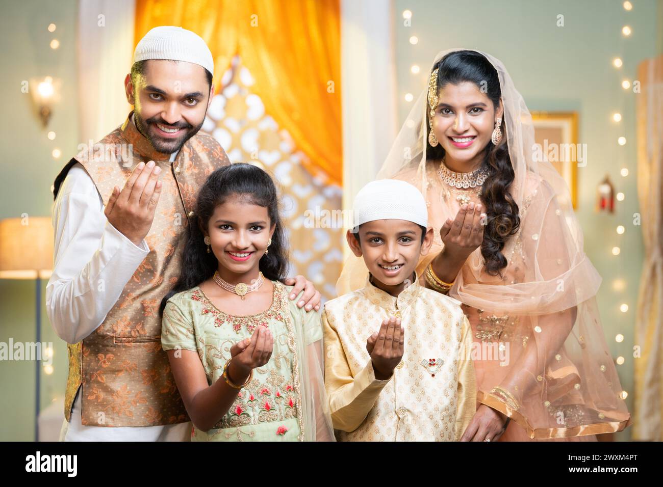 Heureux couple indien souriant avec enfant souhaitant pour le festival du ramadan en disant geste de la main tout en regardant la caméra à la maison - concept de salutation, famille Banque D'Images