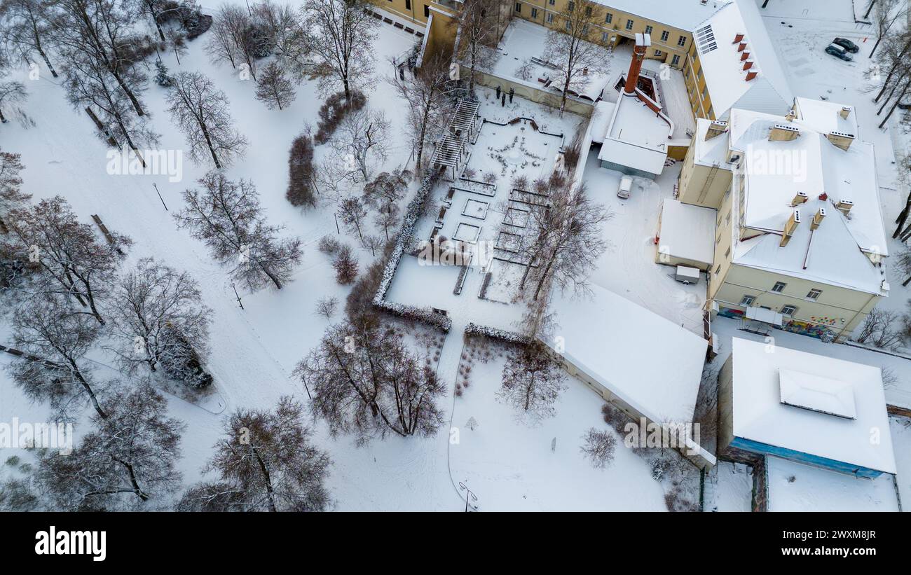 Photographie par drone d'un petit parc public avec une haie couverte de neige dans une ville pendant la journée nuageuse d'hiver Banque D'Images