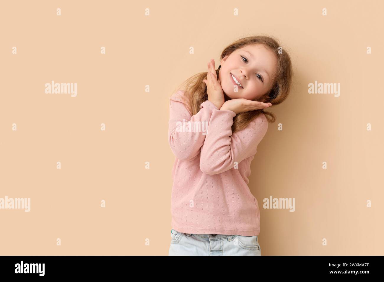 Bonne petite fille sur fond beige. Fête des enfants Banque D'Images