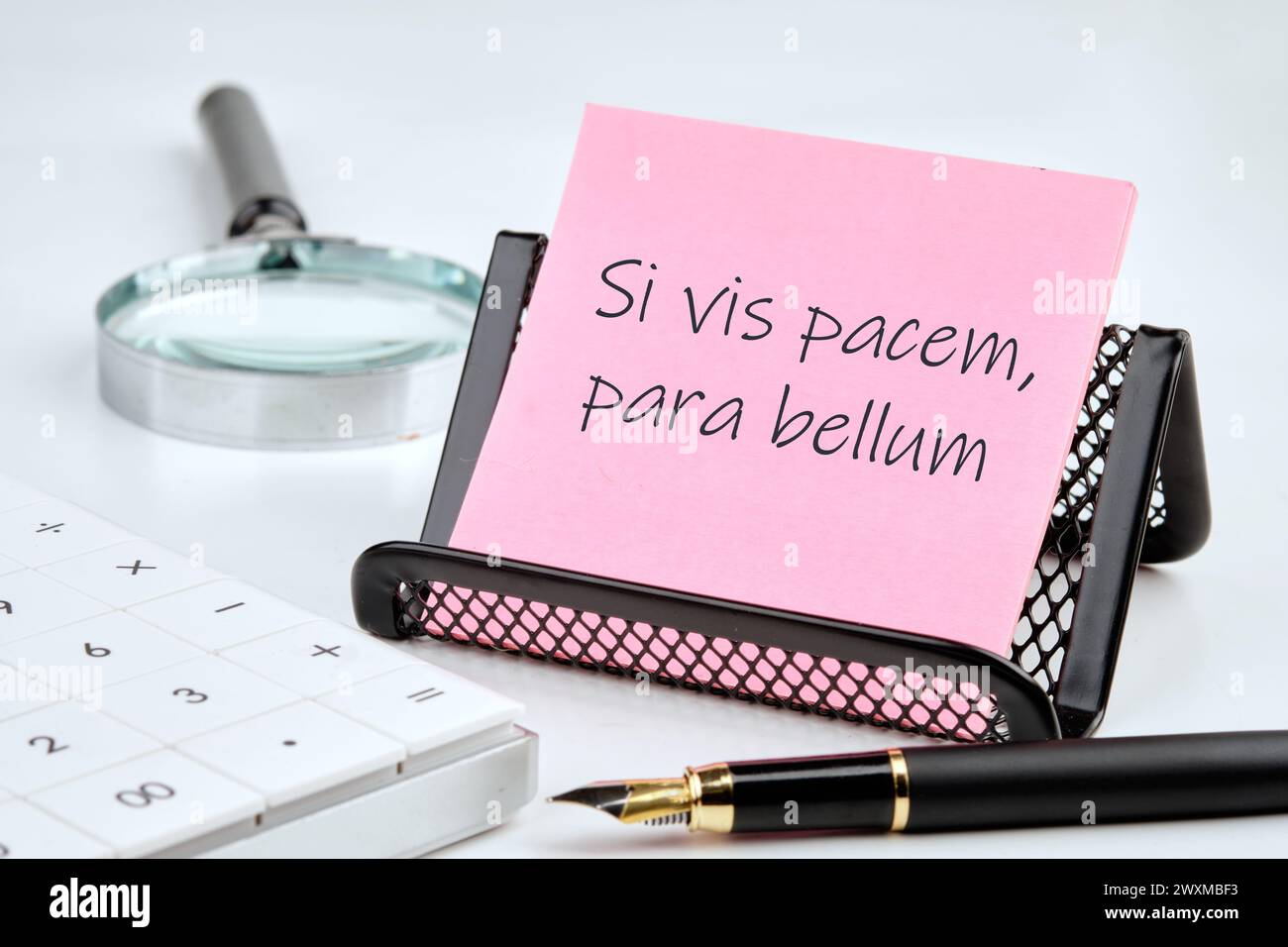 Si vis pacem, para bellum. Phrase latine signifiant si vous voulez la paix, préparez-vous à la guerre. sur un autocollant rose avec des fournitures de bureau sur un fond blanc Banque D'Images