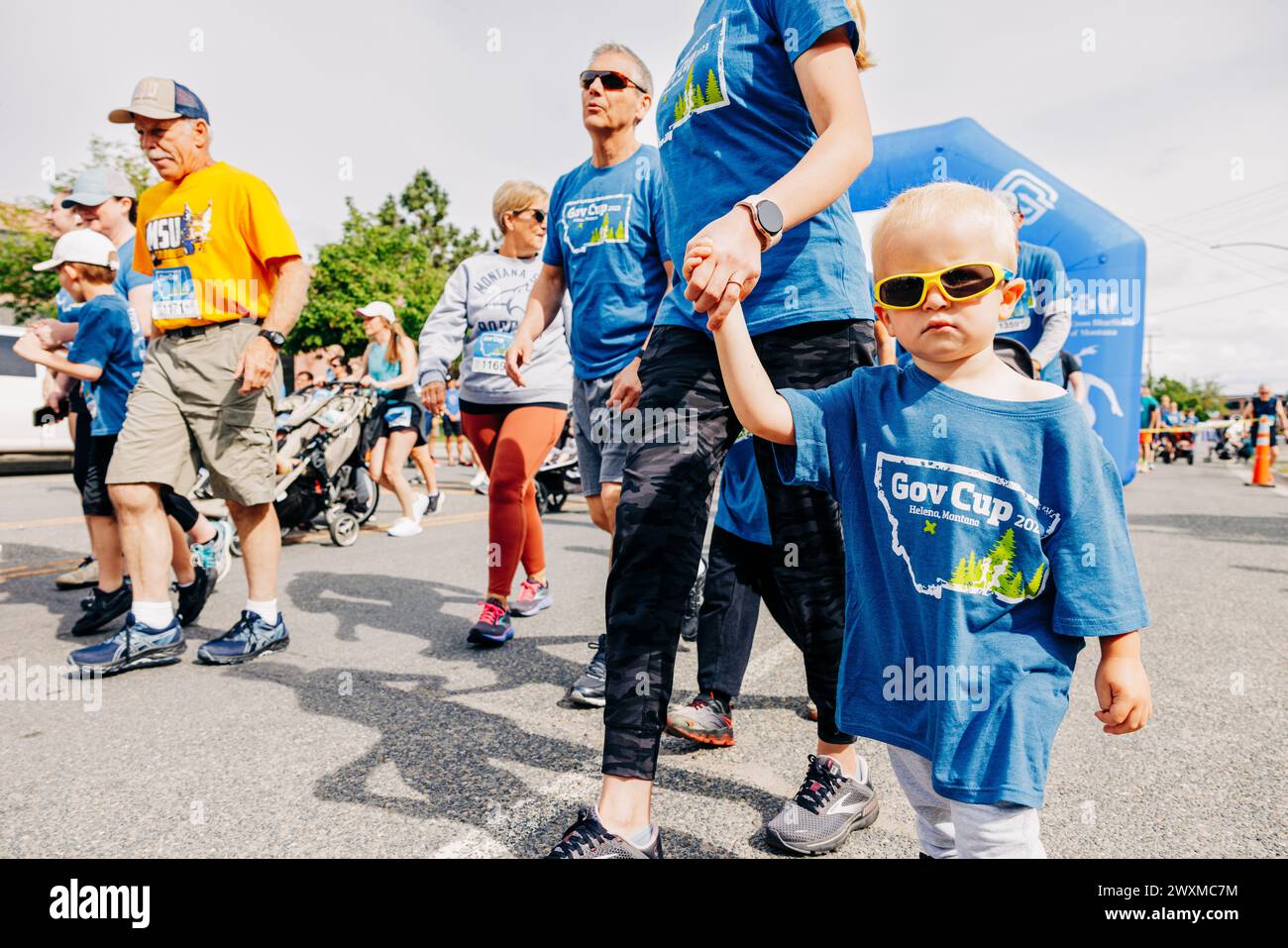Petit garçon avec des lunettes de soleil marchant en marathon avec maman Banque D'Images