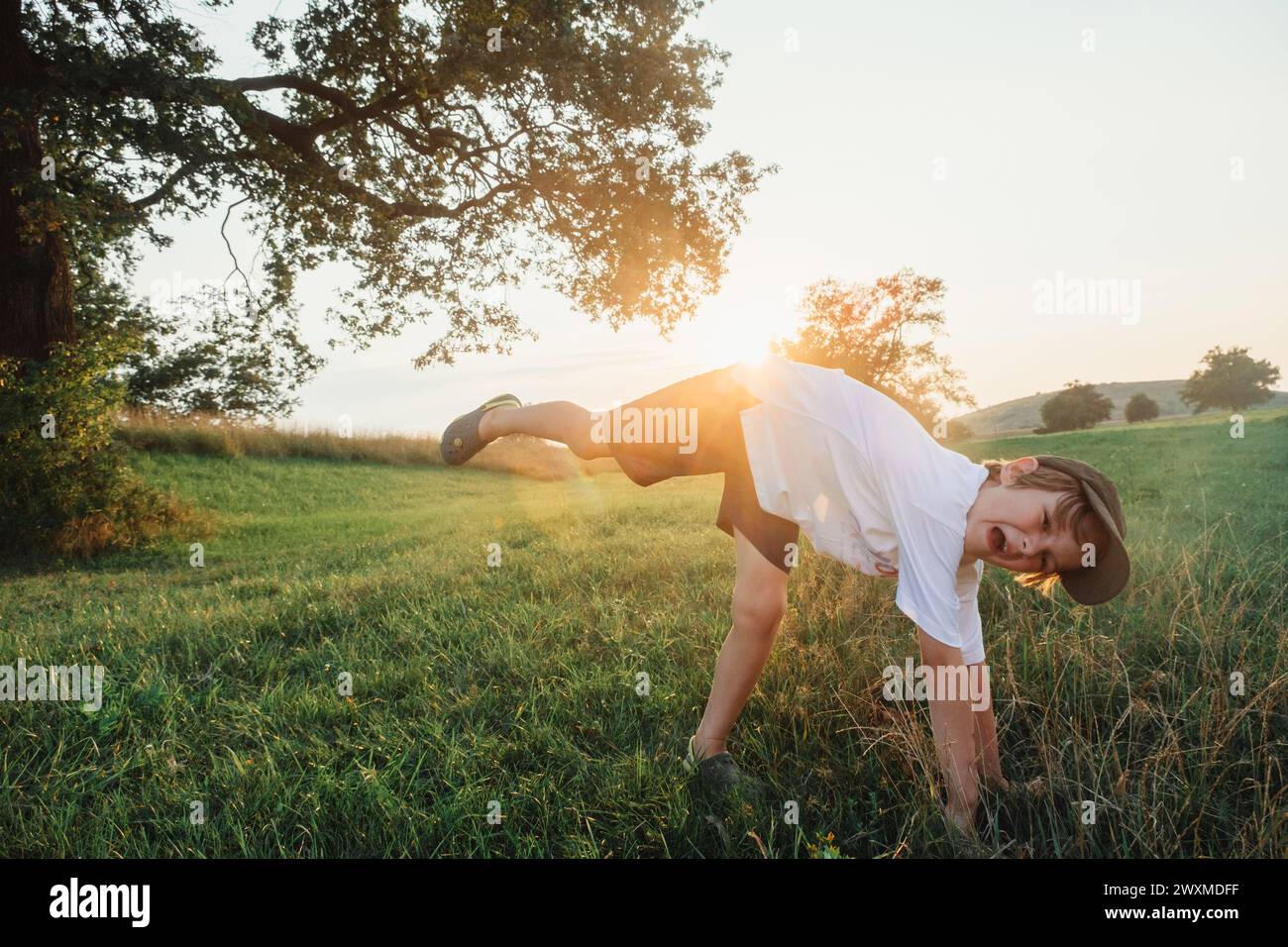 Garçon heureux s'amusant sur le terrain d'herbe portant un t-shirt blanc Banque D'Images