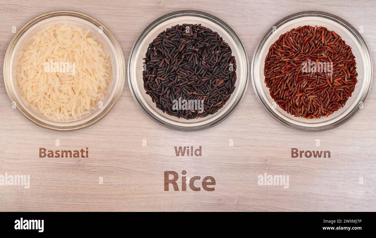 Trois bols transparents présentent différentes variétés de riz - Basmati, Wild et Brown - soigneusement étiquetés, reposant sur une surface en bois lisse. L'assortme Banque D'Images Trois bols transparents présentent différentes variétés de riz - Basmati, Wild et Brown - soigneusement étiquetés, reposant sur une surface en bois lisse. L'assortme Banque D'Images