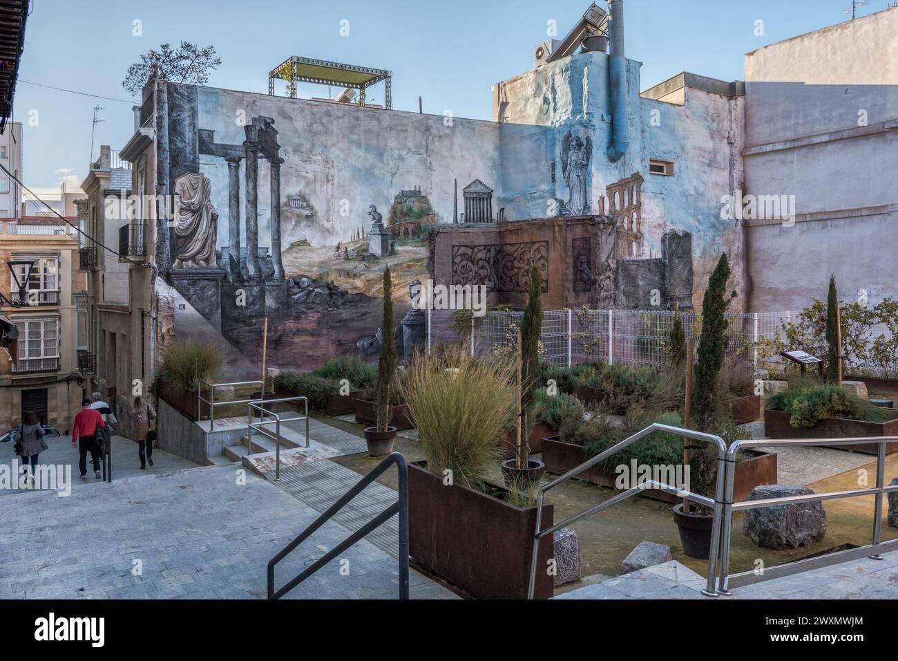 Murs de bâtiments décorés d'un paysage de la Rome antique. Fresque ou peinture murale dans tout le coin d'une place pleine de plantes, Carthagène. Banque D'Images
