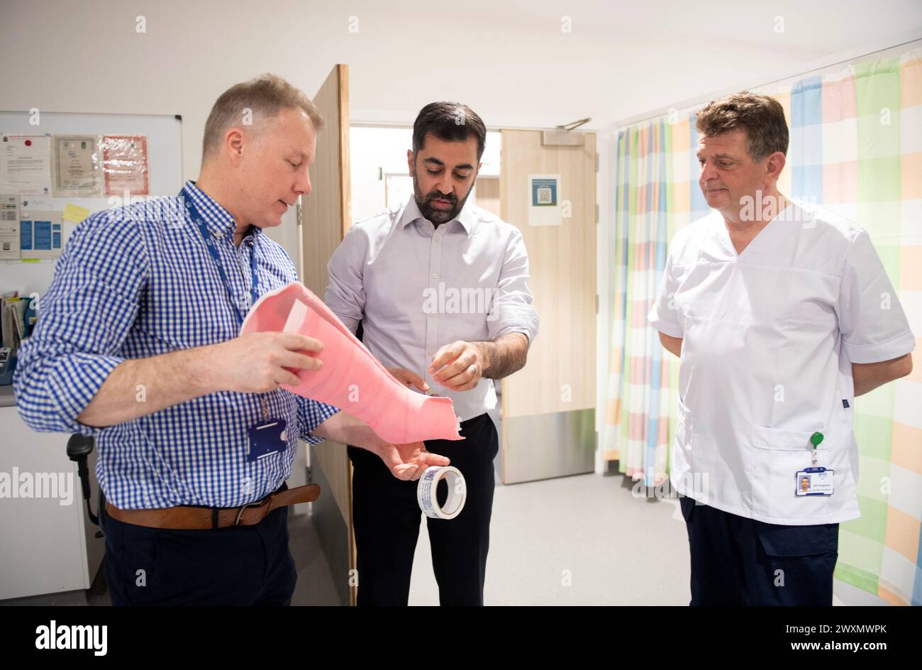 Le premier ministre écossais Humza Yousaf (au centre) aux côtés du chirurgien orthopédique consultant Andy Ballantyne (à gauche) alors qu’ils s’adressent à un membre du personnel lors d’une visite au Centre national de traitement de l’hôpital Victoria de Kirkcaldy, Fife, pour l’annonce d’un investissement visant à réduire les temps d’attente. Date de la photo : lundi 1er avril 2024. Banque D'Images