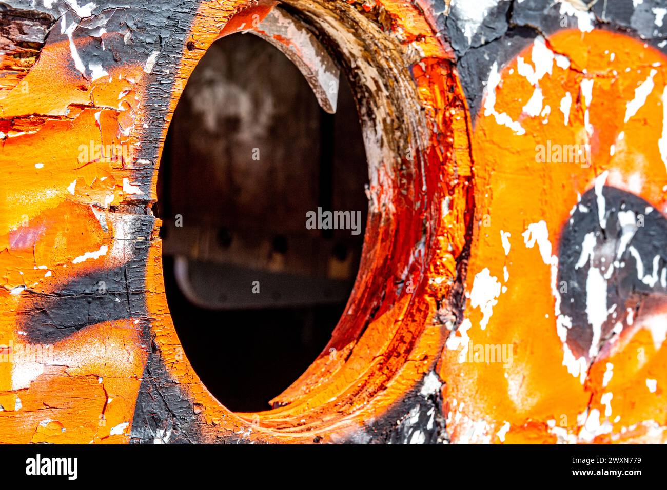 Gros plan du trou où la fenêtre du hublot était dans la coque en bois du vieux bateau endommagé, pelant orange, peinture noire et blanche, journée ensoleillée sur la plage mexicaine Banque D'Images