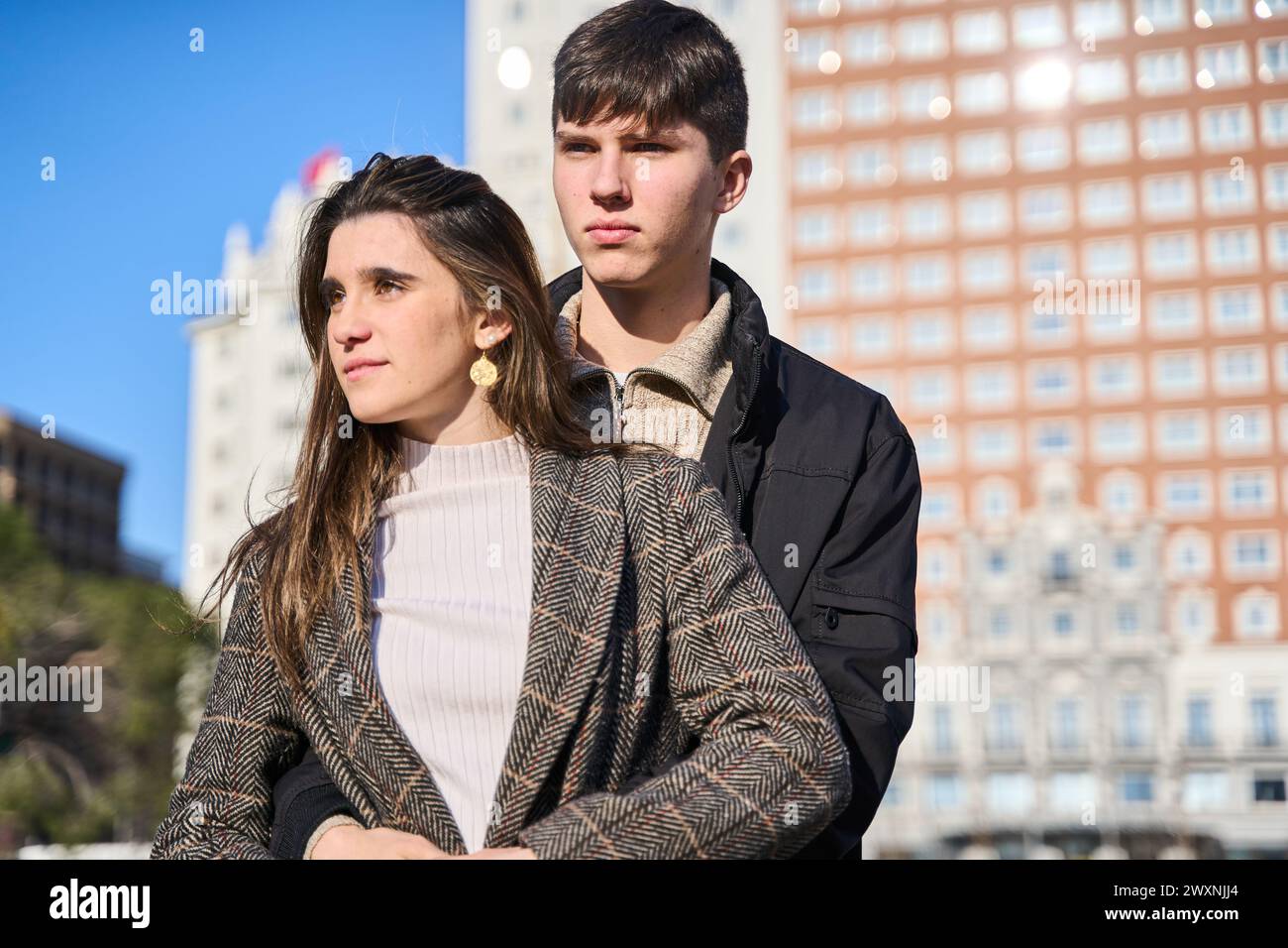Portrait d'un jeune couple caucasien en vêtements décontractés embrassant avec la ville en arrière-plan. Banque D'Images