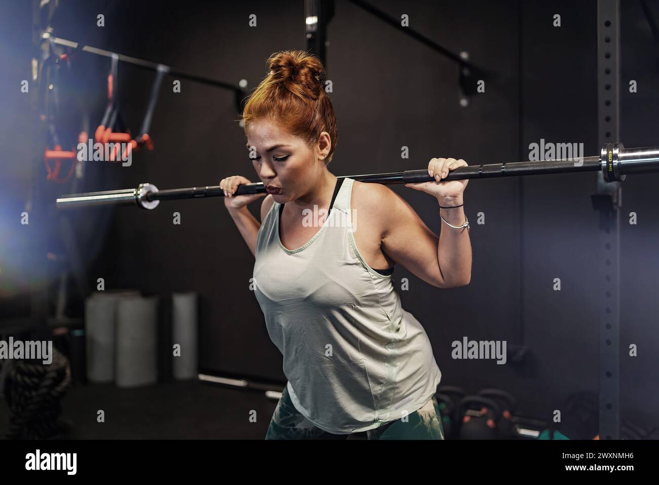 Femme athlétique s'engageant dans une séance d'entraînement de gymnastique intense, mettant en valeur la force et la détermination, dans un contexte d'équipement de gymnastique. Banque D'Images